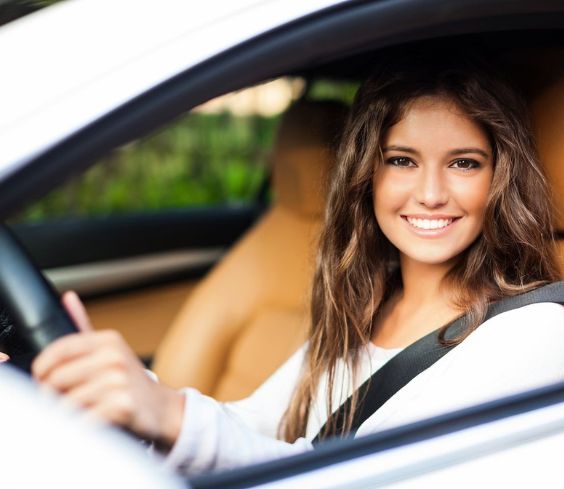 A Girl Is Smiling While Driving A Car